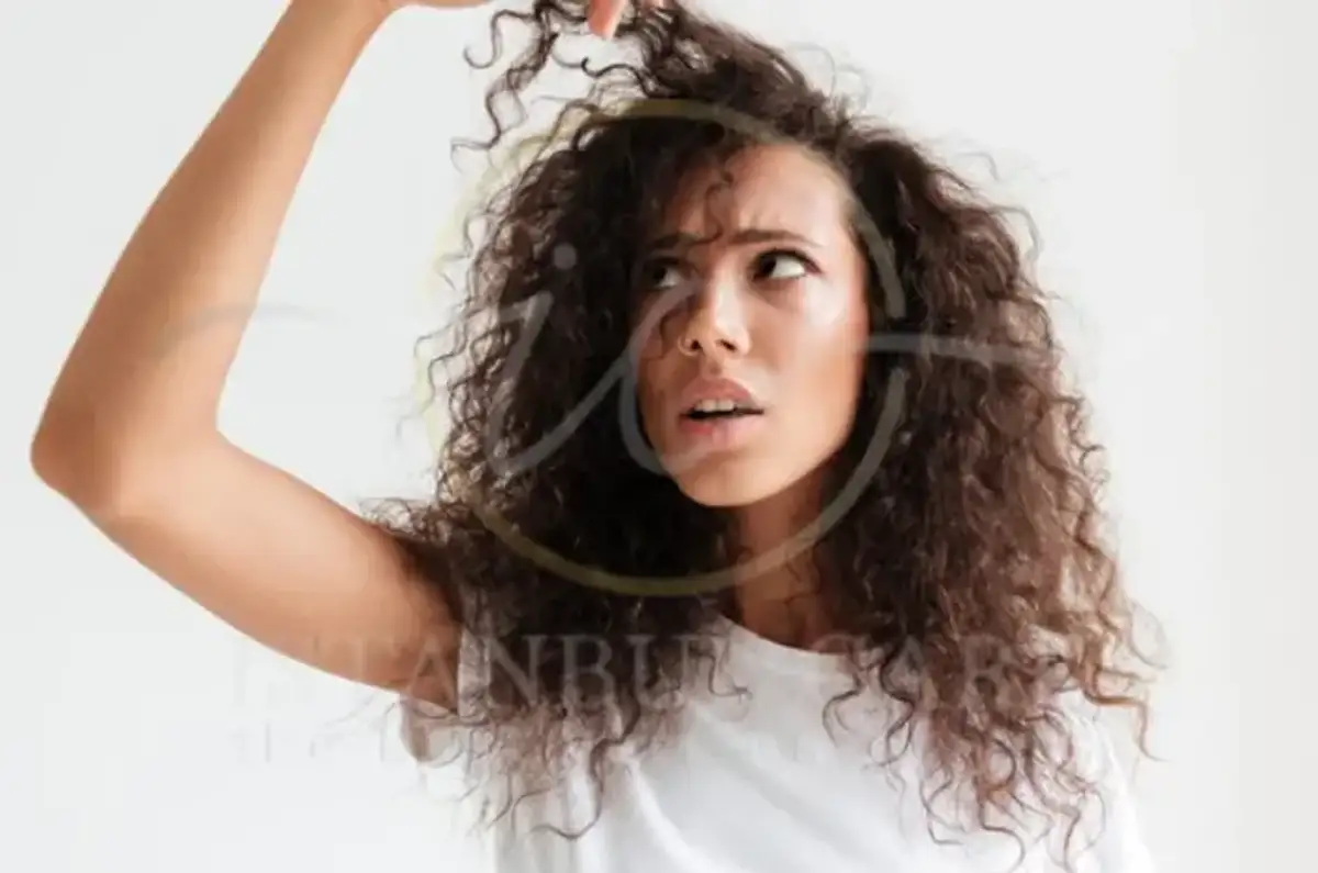Woman examining her dry curly strands, a common frustration with low porosity hair