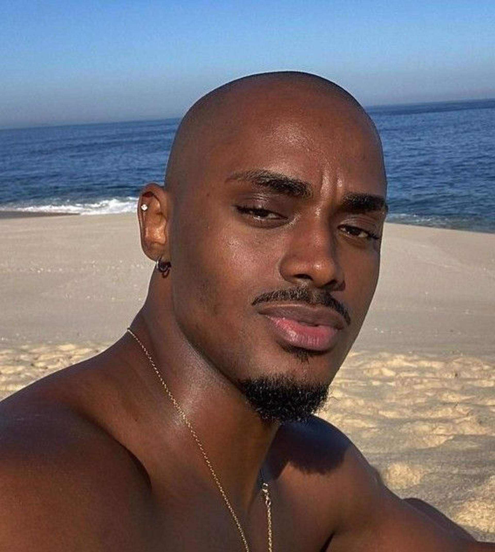 Man with a closely shaved bald head and neat goatee at the beach