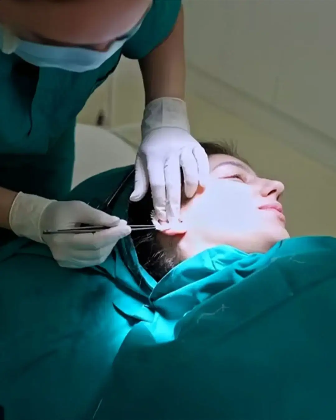 Chirurg przeprowadza otoplastykę u pacjentki.