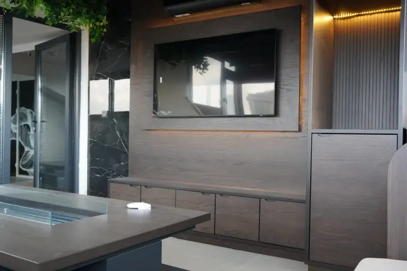 Lounge at the Istanbul Care clinic with a wood-panelled wall, a wall-mounted TV and a table