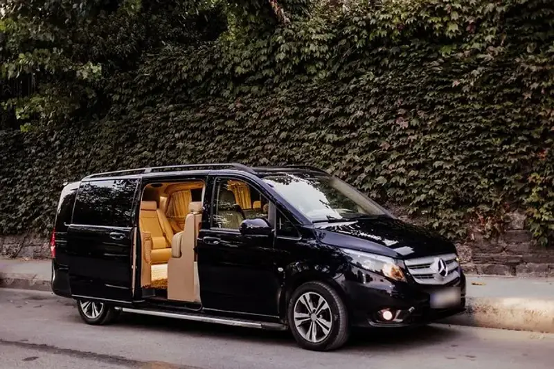 Black passenger van with its sliding door open, showing tan leather seats inside