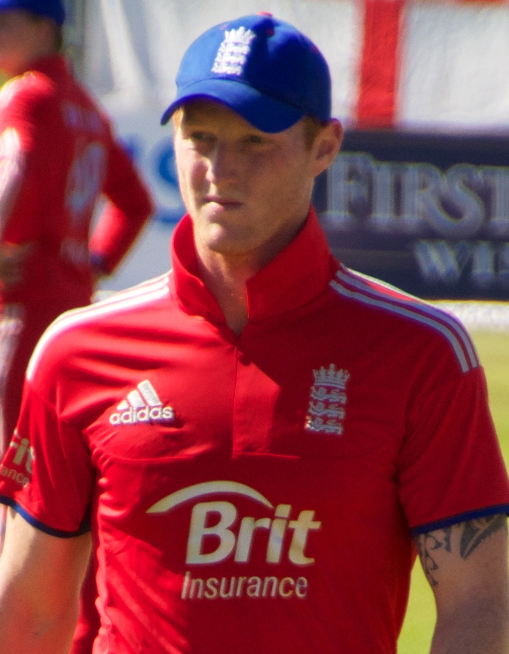 Ben Stokes con il berretto da cricket dell'Inghilterra e la maglia rossa della squadra in campo, con la visiera del berretto che copre completamente fronte e attaccatura dei capelli.